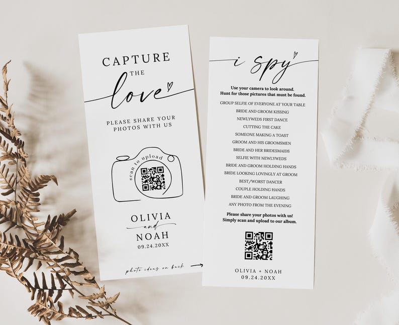 May include: Two white wedding signs with black text. One says "Capture the love" with a camera graphic and QR code. The other says "i spy" with a list of photo prompts and a QR code. Names and a date are at the bottom.