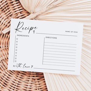 Peut inclure: Une carte de recette vierge avec le mot "Recette" écrit en cursive en haut. La carte comporte des sections pour les ingrédients, les instructions et le nom du plat. Elle indique également "avec amour" en bas.
