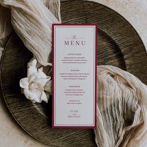 May include: A tall, rectangular wedding menu card with a deep red border and white background. The text reads THE MENU, APPETIZERS, ENTREE, DESSERTS, and the names ELSIE and MICHAEL, along with a list of food items in a dark red serif font.
