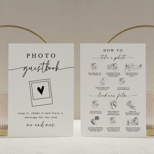 May include: Two white signs with black text and illustrations. The left sign says "PHOTO guestbook" with a black and white illustration of a Polaroid camera. The right sign says "HOW TO take a photo" with black and white illustrations of a Polaroid camera and instructions on how to use it.