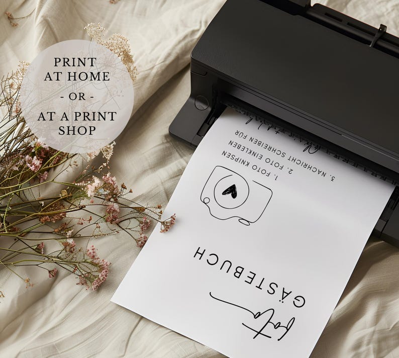 May include: A white sheet of paper with black text and a simple camera illustration. The text reads "G&Auml;STEBUCH", "1. FOTO KNIPSEN", "2. FOTO EINKLEBEN", "3. NACHRICHT SCHREIBEN F&Uuml;R". The paper is being fed into a black printer.
