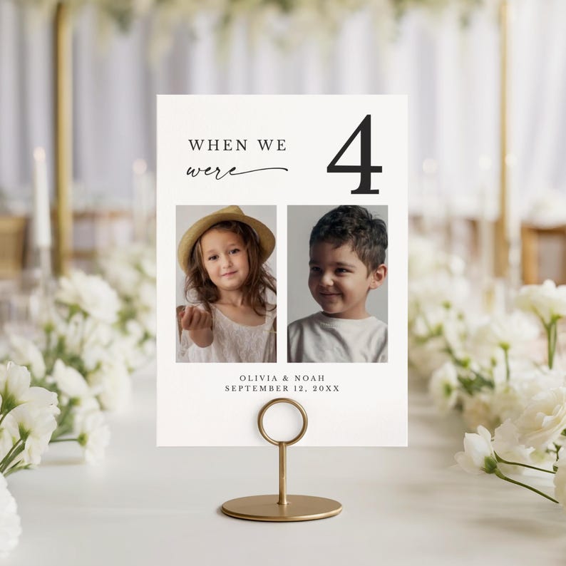 May include: A table number card with the text "When We Were" and the number 4. The card features two photos of children and the names Olivia & Noah with the date September 12, 20XX. The card is held by a gold metal stand.