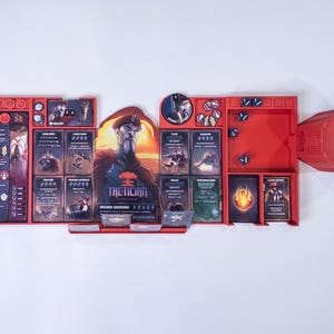May include: A red plastic board game organizer featuring a central character illustration labeled Tactician, multiple slots for game cards, small circular tokens, and six-sided dice. The organizer includes a separate red hexagonal dice tower.