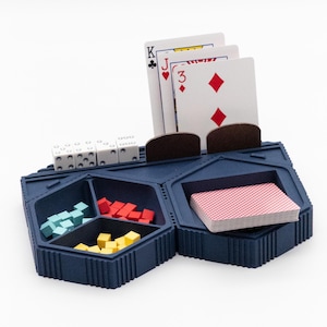 May include: A blue plastic game organizer with compartments for cards, dice, and small game pieces. The organizer has a slot for holding a deck of cards and a separate compartment for dice. The organizer is designed to hold game pieces and cards for a variety of games.