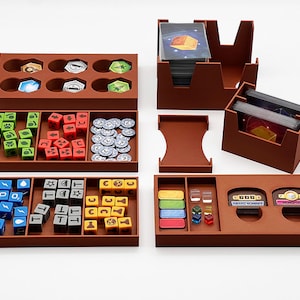 May include: Brown plastic organizer with compartments for storing dice, tokens, and cards. The organizer is designed for a board game and includes sections for different types of game components.