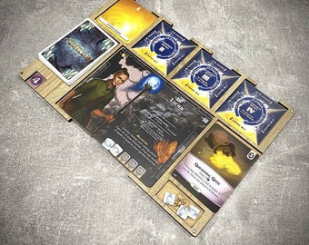 Puede incluir: Un tablero de juego de madera con compartimentos para cartas y dados. El tablero presenta un diseño azul y dorado con el texto "Quickening Quoth" y "Lucien".
