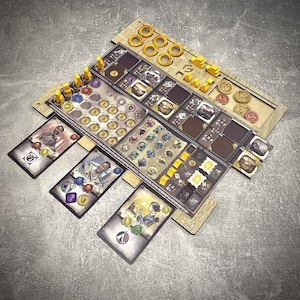 May include: A wooden board game organiser with multiple compartments and card slots. The organiser holds various game pieces, including yellow player tokens, gold coins, and cards with illustrations. The design is a light brown colour.