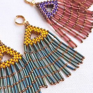 Könnte beinhalten: Nahaufnahme von drei Paar Perlenquasten-Ohrringen. Die Ohrringe haben eine dreieckige Oberseite mit einem Perlenmuster und langen, herabhängenden Quasten. Die Farbpalette umfasst gelbe, blaue, violette und rosa Perlen mit goldfarbenen Akzenten. Der Text "Triangle Tassel Earrings 2024" ist sichtbar.