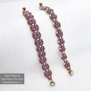 May include: Two beaded bracelets with a floral design. The bracelets feature lavender-colored beads, silver beads, and bronze-colored accents. The bracelets are approximately 7 inches long.