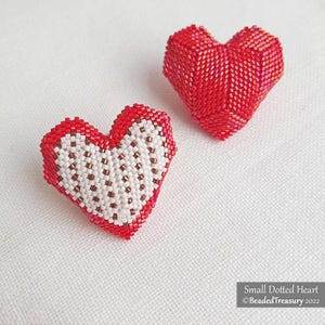Puede incluir: Dos adornos en forma de corazón hechos con cuentas. Uno es rojo con un diseño punteado blanco y marrón, y el otro es rojo liso. Estos adornos hechos a mano son ideales para el Día de San Valentín u otras ocasiones especiales.