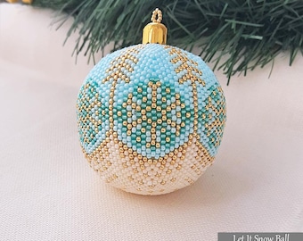 May include: A beaded Christmas ornament with a gold cap. The ornament is spherical, featuring a pattern of light blue, teal, gold, and white beads. The text "Let It Snow Ball" is visible on the bottom right.