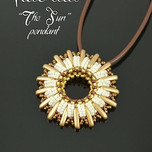 May include: A handmade pendant necklace with a sunburst design. The pendant features gold, white, and brown beads arranged in a circular pattern. The text "Tutorial The Sun pendant" is visible. The necklace has a brown leather cord.