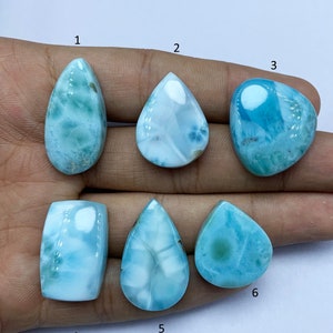 May include: Six different blue and white gemstone cabochons, labeled 1 through 6, are displayed on a hand. The cabochons are all teardrop shaped except for the one labeled 4, which is rectangular.