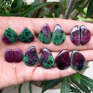 Op de afbeelding: Zes paar groene en rode edelsteen cabochons, genummerd van 1 tot en met 6. De cabochons zijn in verschillende tinten groen en rood, sommige hebben een meer paarse tint.