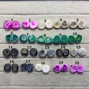May include: Twenty pairs of gemstone cabochons are displayed, each with a distinct colour and pattern. The stones are arranged in rows, featuring pink, green, white, and grey hues. The cabochons are numbered from 1 to 20.