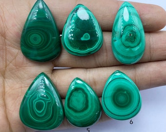 Puede incluir: Seis cabujones de malaquita verde en forma de lágrima. Las piedras tienen un patrón de remolino de verde y negro.