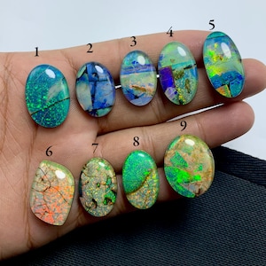 May include: Nine oval-shaped opal gemstones with various colors and patterns, including green, blue, and white. The stones are numbered 1 through 9.