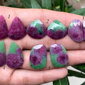 Puede incluir: Diez cabujones de piedras preciosas en varios tonos de verde y rosa. Las piedras están dispuestas en pares, numeradas del 1 al 5.