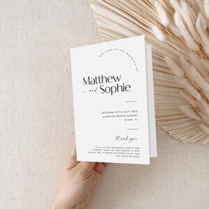May include: A white wedding invitation card with black text. The card reads "Welcome to the wedding of Matthew and Sophie" and includes the date, location, and a thank you message.
