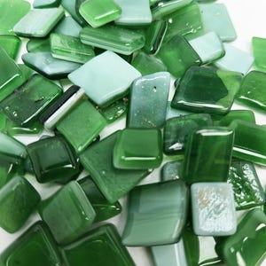 May include: A selection of green glass mosaic tiles in various shapes, including squares and rectangles. The tiles range in shades from light seafoam to deep forest green, with a glossy finish. Suitable for craft projects.