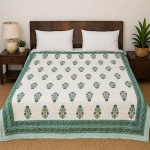 Puede incluir: Un edredón con estampado floral blanco y verde azulado sobre una cama. El edredón presenta un diseño floral repetido en verde azulado y verde oliva. El borde tiene un patrón geométrico verde azulado y verde oliva. La cama tiene almohadas blancas y un cabecero de madera oscura.