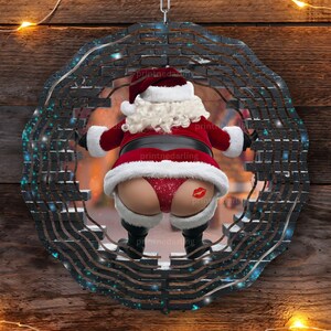 May include: A black and blue circular metal ornament with a brick pattern. A Santa Claus figure is seen in the center of the ornament, wearing a red suit and a white beard. The Santa Claus figure is partially obscured by the brick pattern.