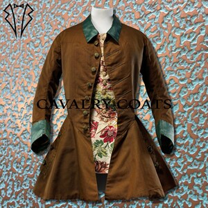 May include: A brown coat with a green collar and cuffs. The coat has a fitted waist and a flared skirt. The coat is buttoned up the front with several buttons. The coat is being displayed on a mannequin.