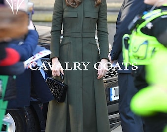 May include: An olive green coat with a tailored fit, featuring a high collar, two chest pockets, and a belted waist. The coat is knee-length and has a pleated skirt. The text "CAVALRY COATS" is visible on the coat.