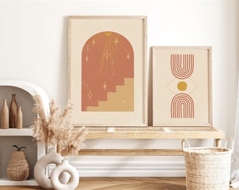 Peut inclure: Deux affiches encadrées dans des cadres en bois clair. La plus grande affiche présente une arche terracotta avec des escaliers et des étoiles rayonnantes. La plus petite affiche montre deux arcs-en-ciel terracotta superposés avec un cercle jaune central.