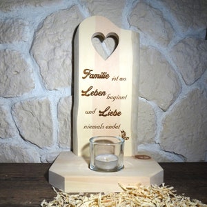 Könnte beinhalten: Holz-Kerzenhalter mit einem Herz-Ausschnitt und dem Text "Familie ist wo Leben beginnt und Liebe niemals endet". Ein kleiner Glas-Kerzenhalter sitzt auf der Basis.