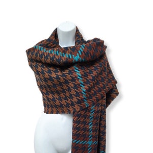 May include: A brown and blue plaid scarf with a houndstooth pattern. The scarf is draped over a white mannequin.