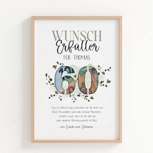 May include: A framed print featuring the text "WUNSCH Erfüller FUR THOMAS". The number "60" is central, filled with a collage of colourful currency. The print includes a message wishing the recipient happiness and health. The frame is a light wood colour.