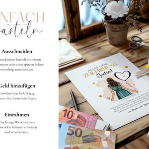 May include: A printed card with the text "Alles Liebe Zur Firmung Julia!" is being cut with a yellow utility knife. The card features an illustration of a person in a green dress holding a heart-shaped balloon. Euro banknotes are visible.