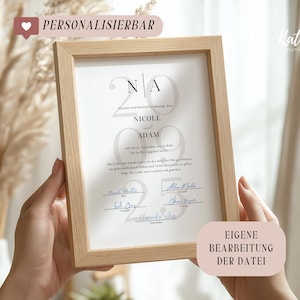May include: A framed wedding print with the names "Nicole" and "Adam" and the date "2022". The print is in a light wood frame and includes signatures. Text on the frame reads "PERSONALISIERBAR" and "EIGENE BEARBEITUNG DER DATEI".