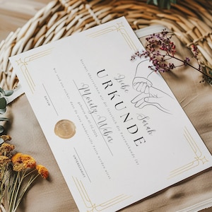 May include: A white certificate with gold accents and a black border. The certificate reads "Liebe Sarah URKUNDE" and "hiermit &uuml;berreichen wir dir feierlich die Patenurkunde f&uuml;r Moritz Weber geboren am 01.02.2024 Wir sind uns sicher, dass du eine wundervolle Patin werden wirst. DATUM UNTERSCHRIFT".