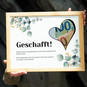 May include: A framed white card with the text "Geschafft!" and a heart-shaped cutout filled with euro bills. The card also includes the text "Herzlichen Gl&uuml;ckwunsch zum wohlverdienten Ruhestand. Wir w&uuml;nschen dir das Beste f&uuml;r die Zukunft. Du wirst uns fehlen!" and a watercolor illustration of eucalyptus leaves.