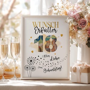 May include: A framed print with the words "Wunsch Erf&uuml;ller 18 Alles Liebe zum Geburtstag!" in gold and black. The number 18 is colourful. Two champagne flutes are in the foreground, and a bouquet of flowers is in the background.