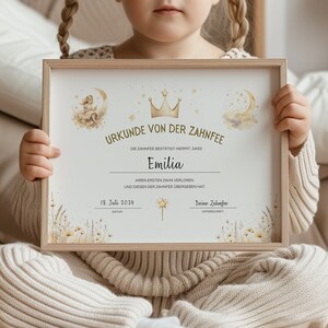 Puede incluir: Un certificado enmarcado con una corona dorada y estrellas, anunciando que Emilia ha perdido su primer diente. El certificado est&aacute; decorado con una ilustraci&oacute;n de acuarela de un hada y flores.