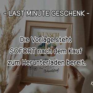 May include: A framed print held by hands, with German text including "LAST MINUTE GESCHENK" and "SOFORT nach dem Kauf". The frame is light brown, and the background is a neutral colour. The print is for a birthday.