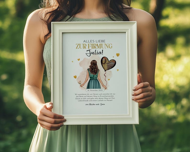 May include: A framed print with the text "ALLES LIEBE ZUR FIRMUNG Julia!" in gold lettering. The artwork features a cartoon illustration of a person holding a heart-shaped balloon. The frame is white.