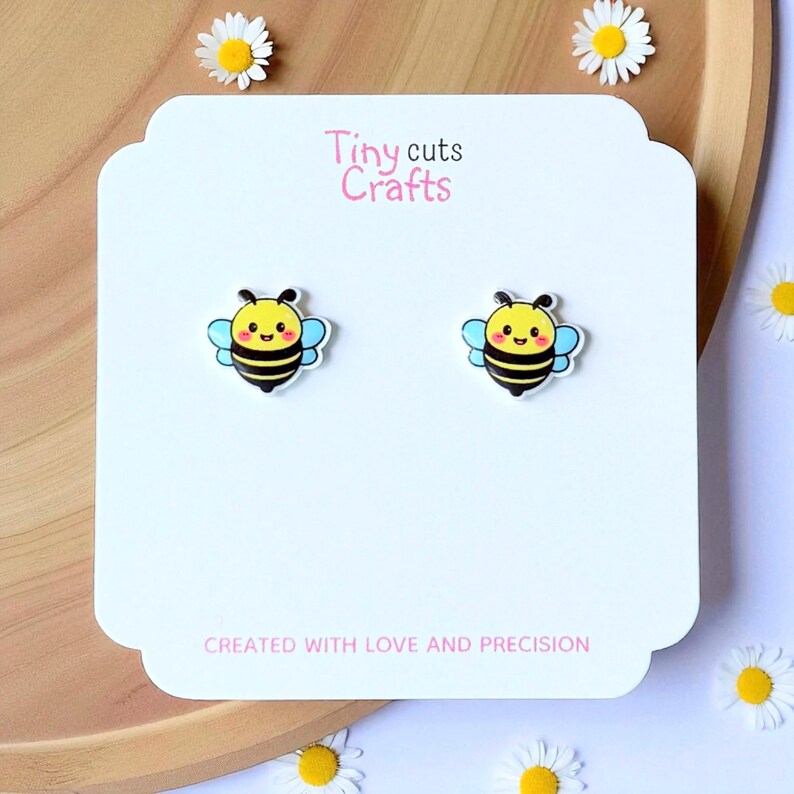Kawaii bee stud earrings with smiling yellow face, black stripes, blue wings, resin gloss top, white acrylic base, hypoallergenic posts gift for her