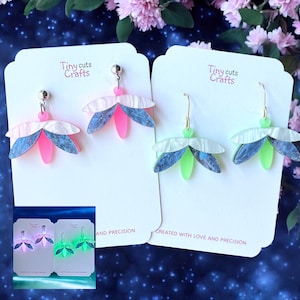 May include: Earrings with a floral design in pink, blue, and white, displayed on white cards. The earrings have a layered petal design with a silver post. The text "Tiny cuts Crafts" is visible on the cards. The earrings are shown in a variety of colors.