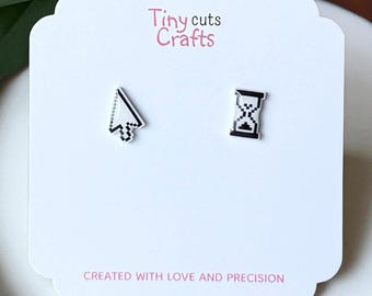 May include: A pair of stud earrings on a white card. One earring is a black and white computer cursor, the other is a black and white hourglass. The card has the text "Tiny cuts Crafts" and "CREATED WITH LOVE AND PRECISION".