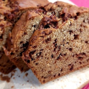 Peut inclure: Gros plan sur une miche de pain aux bananes avec des pépites de chocolat. Le pain est tranché et montre la texture de la mie et des pépites de chocolat.