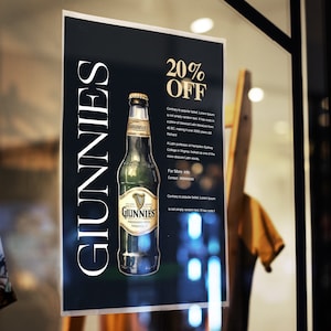 Op de afbeelding: Een zwart-wit bord met de tekst "Guinness" in wit en "20% Korting" in goud. Op het bord staat een fles Guinness-bier afgebeeld.