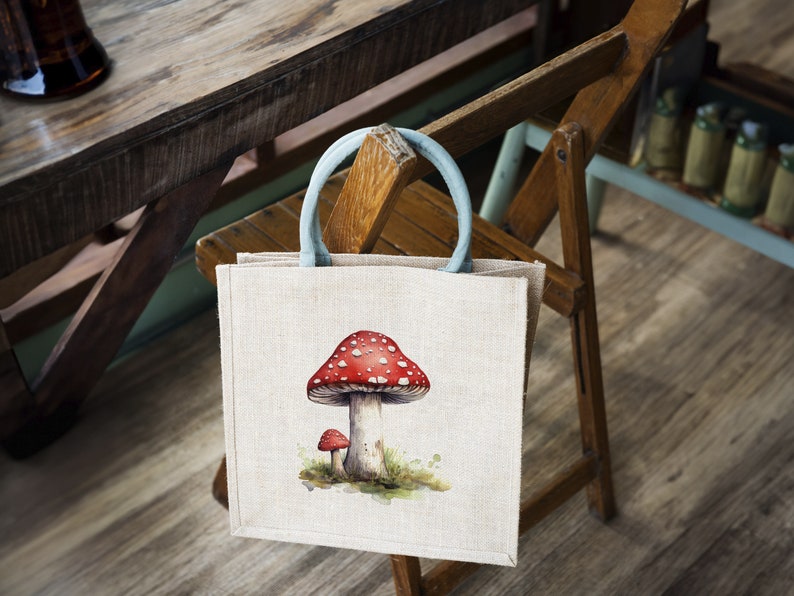 May include: A beige tote bag with a blue handle and a red and white mushroom illustration. The bag is hanging on a wooden chair.
