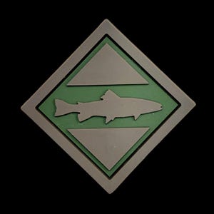 May include: A square patch with a gray border and a green center. Inside the green center is a gray fish silhouette, with gray triangles above and below the fish. The patch is set against a black background.