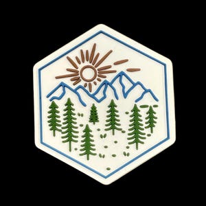 May include: A white, hexagonal sticker with a nature-themed design. The design features a brown sun, blue mountains, green trees, and a blue border. The sticker is on a black background.