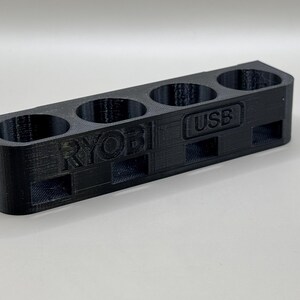 K&ouml;nnte beinhalten: Schwarzer Plastik-Organizer mit f&uuml;nf F&auml;chern zum Aufbewahren von Batterien. Der Organizer tr&auml;gt die Aufschrift "RYOBI" und "USB".