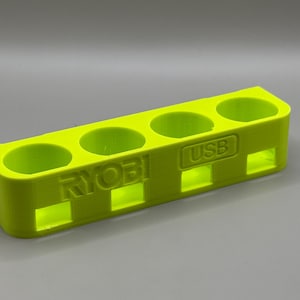 K&ouml;nnte beinhalten: Ein leuchtend gelber Plastik-Organizer mit f&uuml;nf F&auml;chern zum Aufbewahren von Batterien. Der Organizer tr&auml;gt die Aufschrift "RYOBI" und "USB".